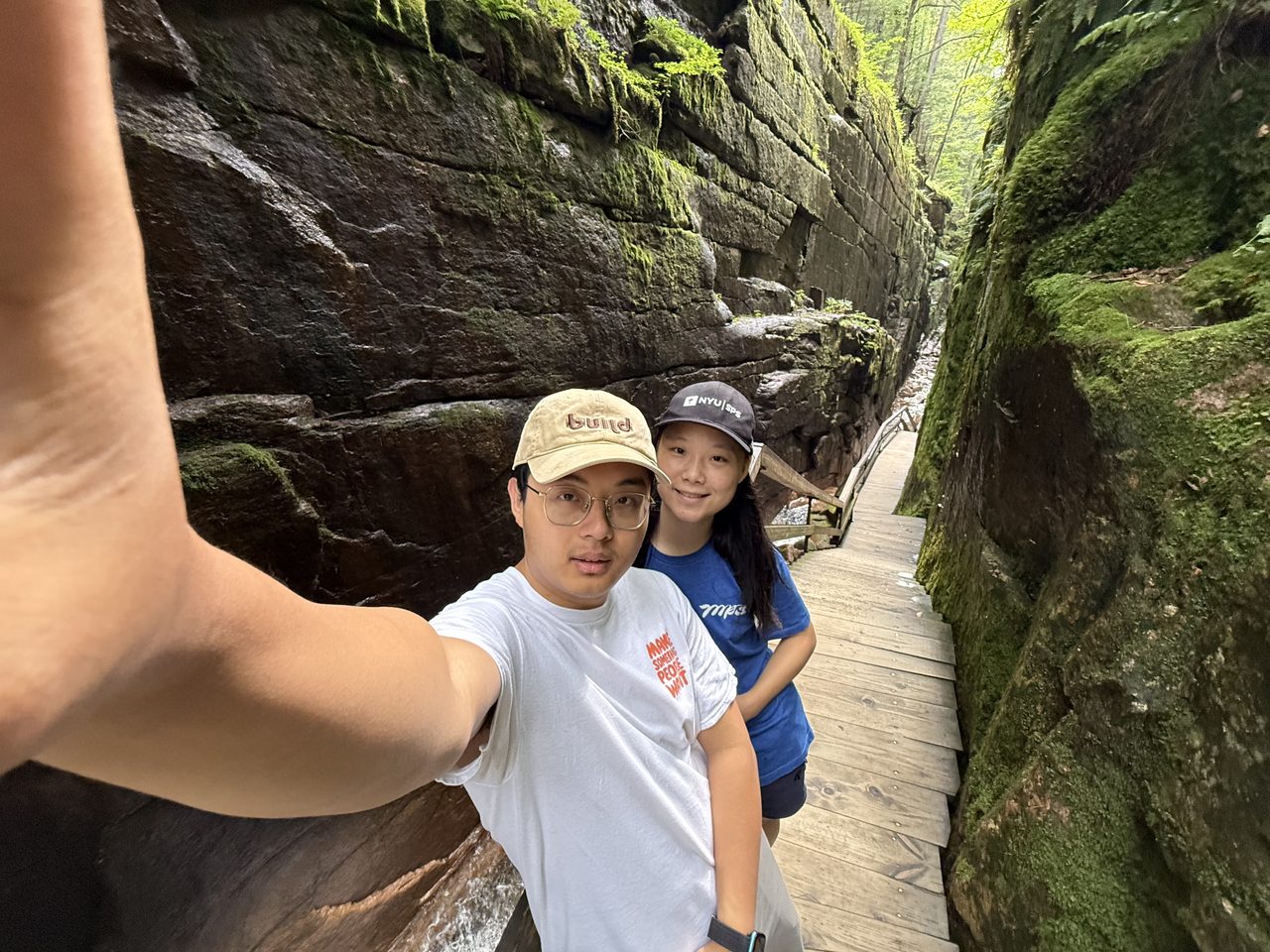 A view down a narrow gorge with boardwalks, a stream, and visitors between high rock walls.