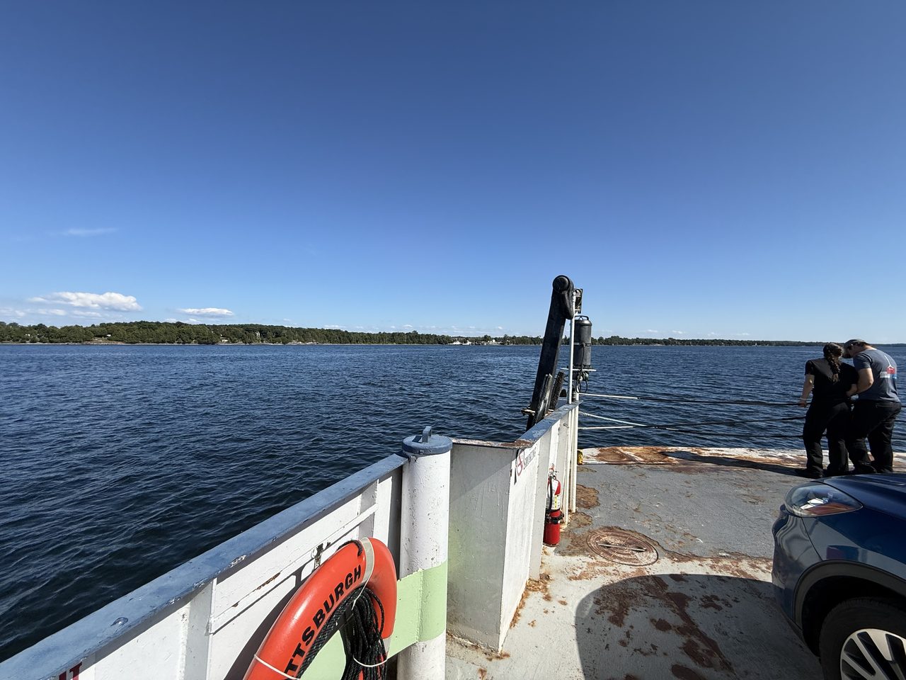 Open lake water under a clear blue sky with distant green hills.