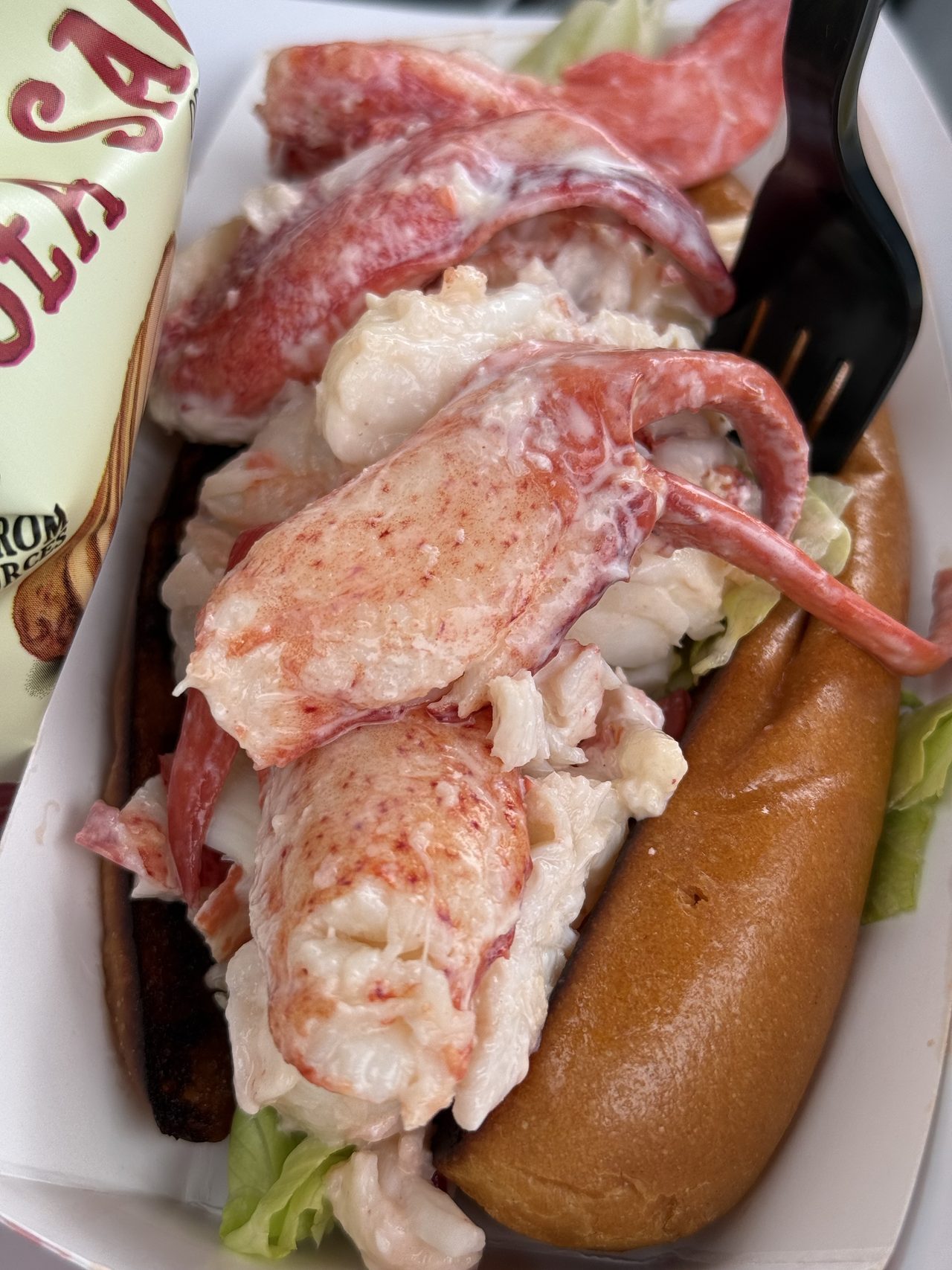 Close view of a lobster roll packed with claw and tail meat in a split-top bun.
