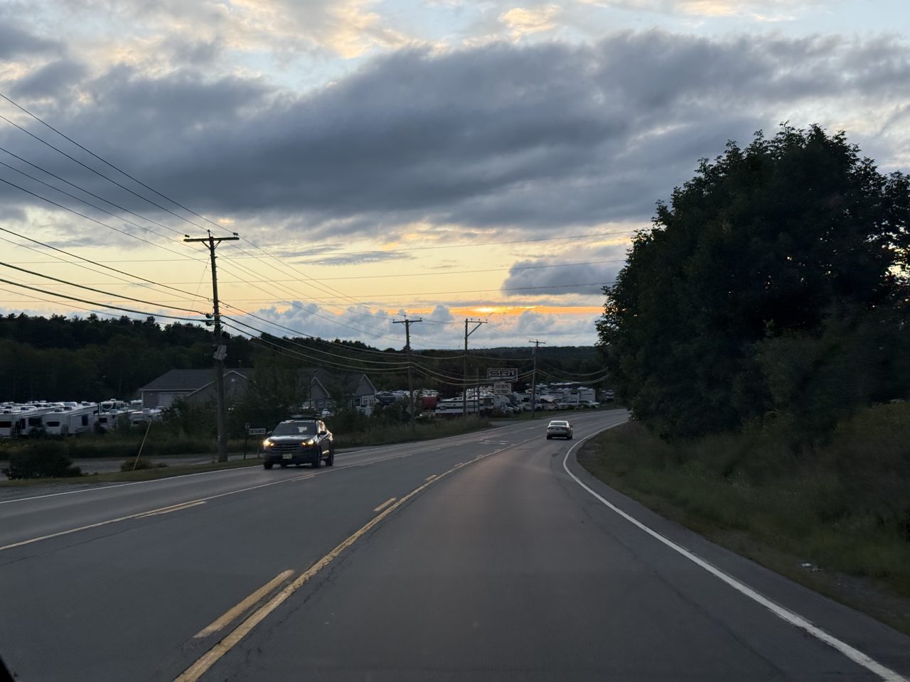 A road at dusk beside an RV dealership with golden light on the horizon.